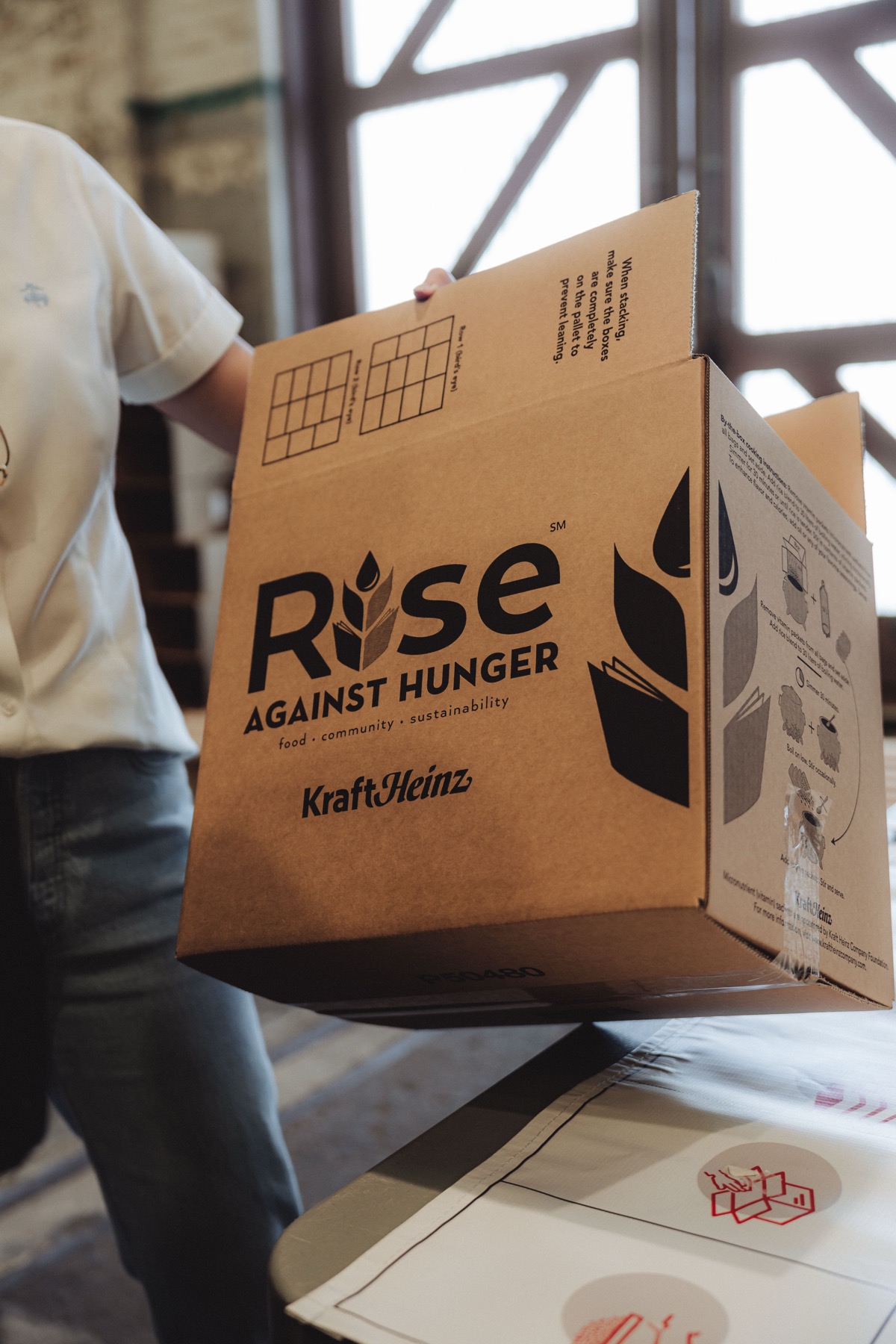 Volunteer carrying a Rise Against Hunger meal-packing box