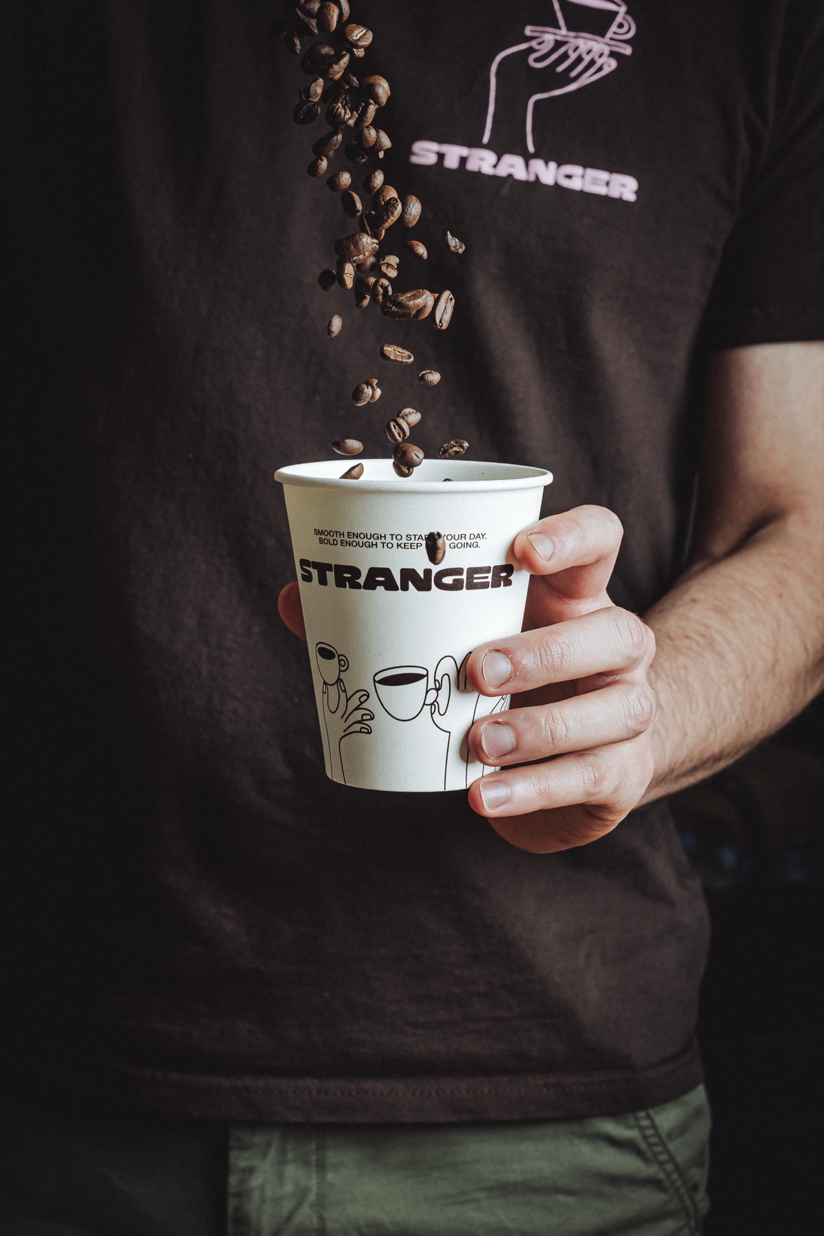 Coffee beans pouring into a Stranger Espresso cup