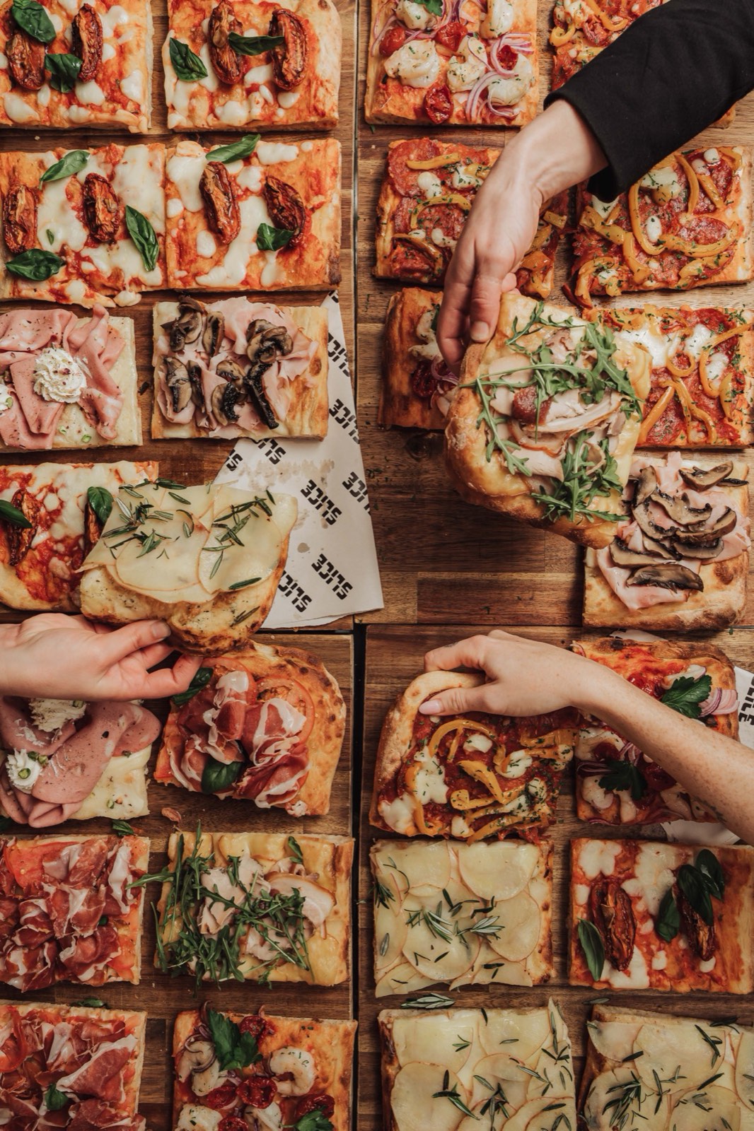Overhead spread of square-cut pizza being shared
