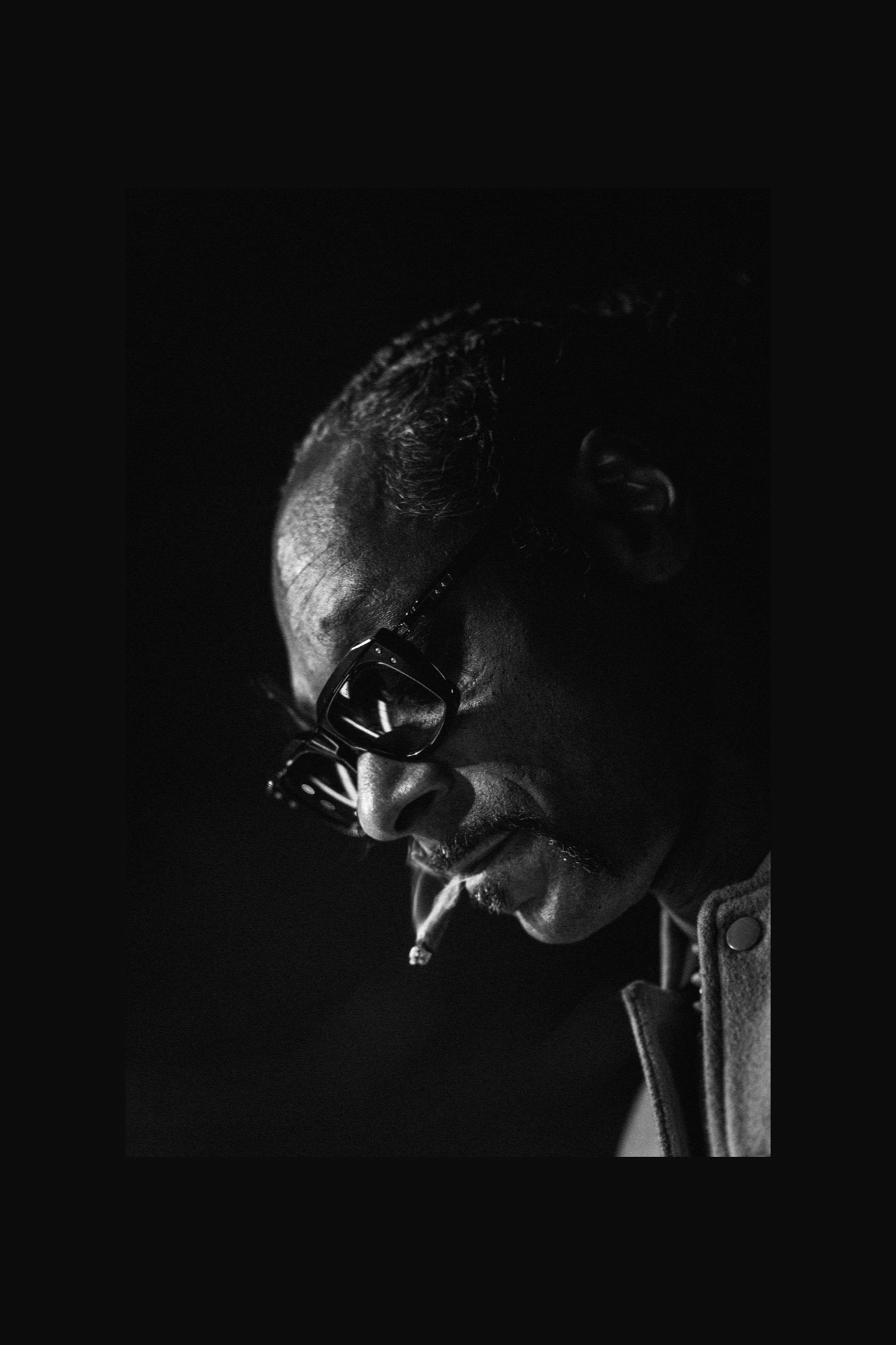 Black and white portrait of a performer lowering his sunglasses