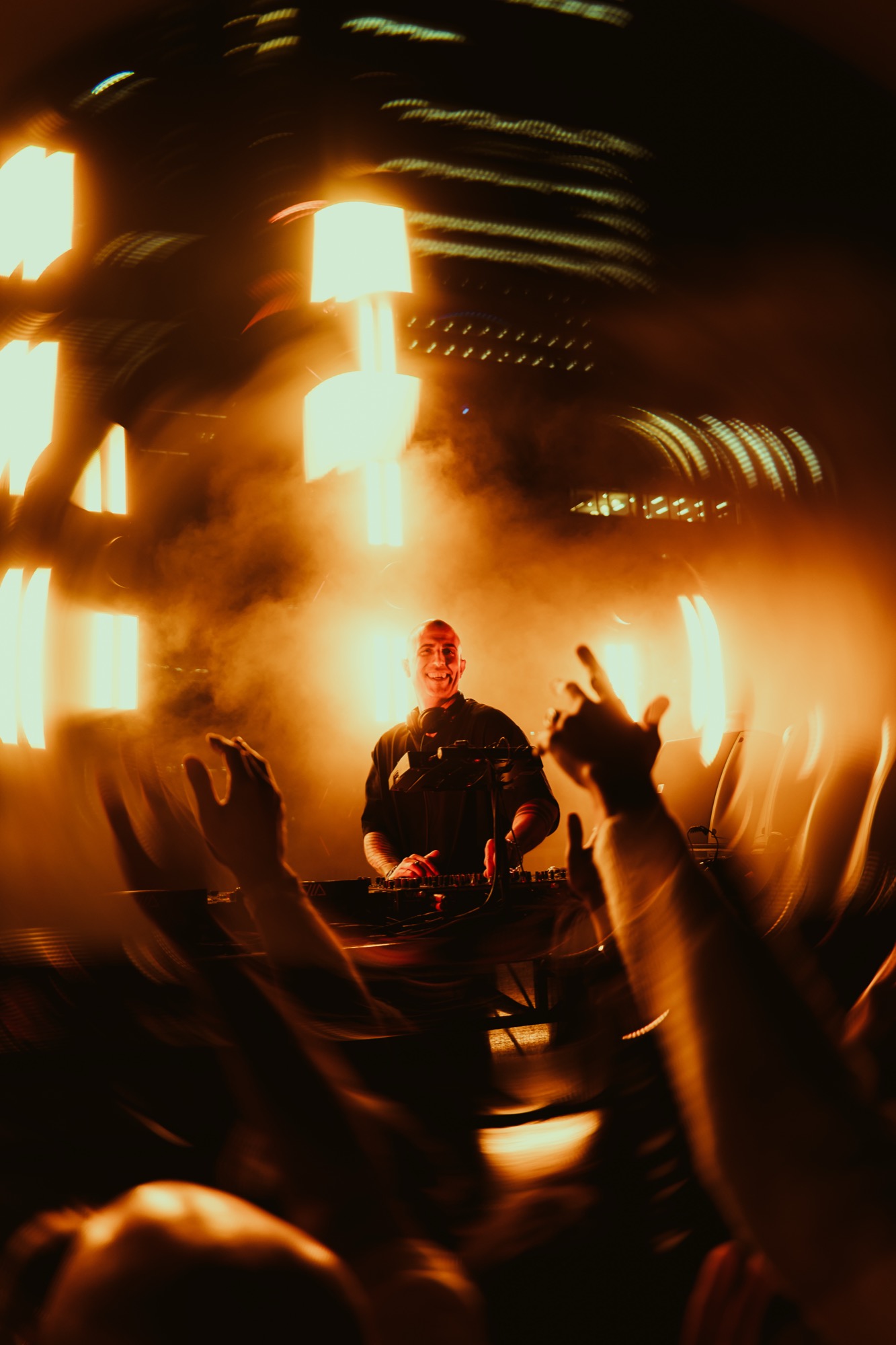 DJ raising the crowd under amber strobe light