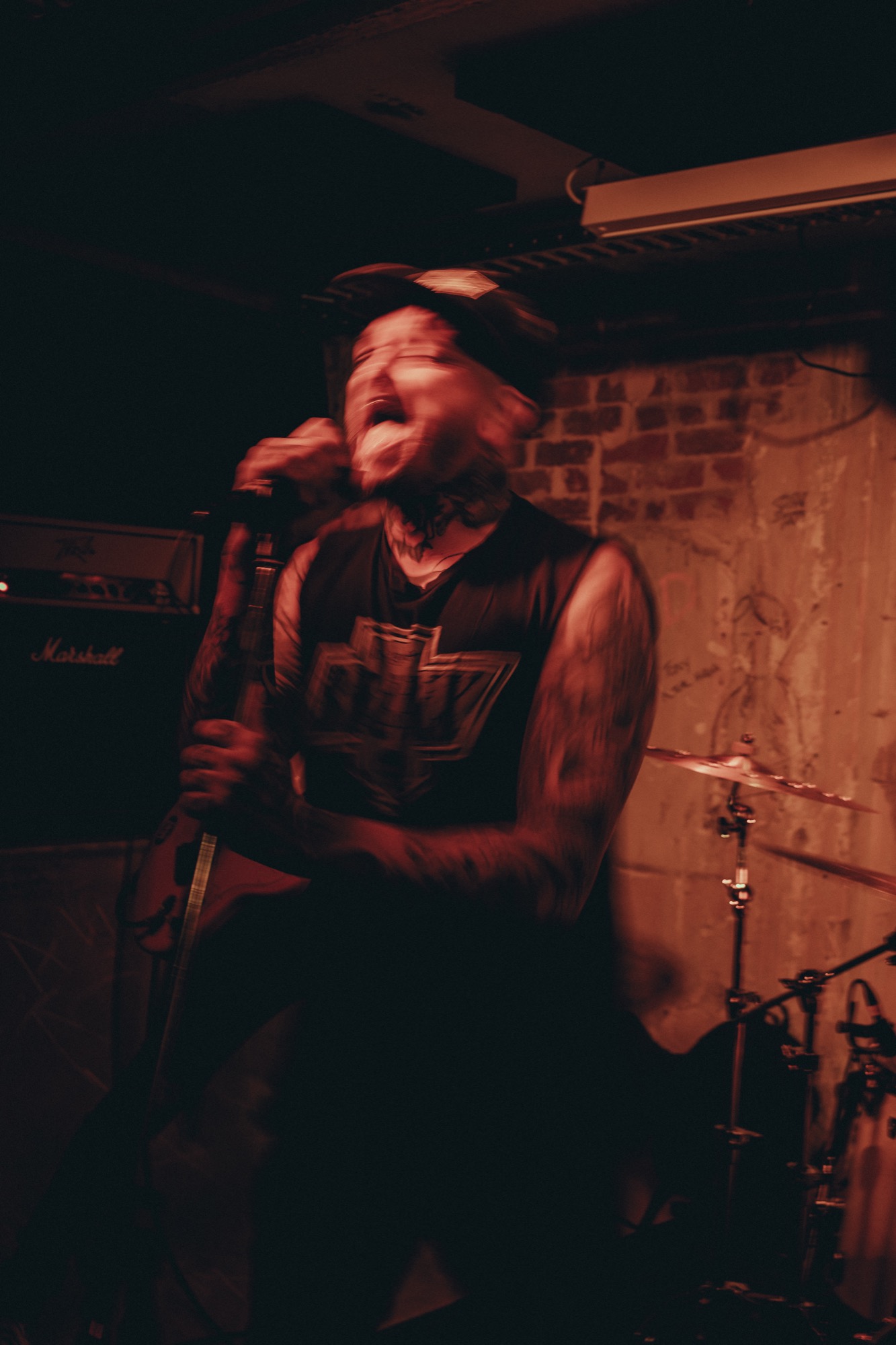 Hardcore vocalist mid-scream in red stage light