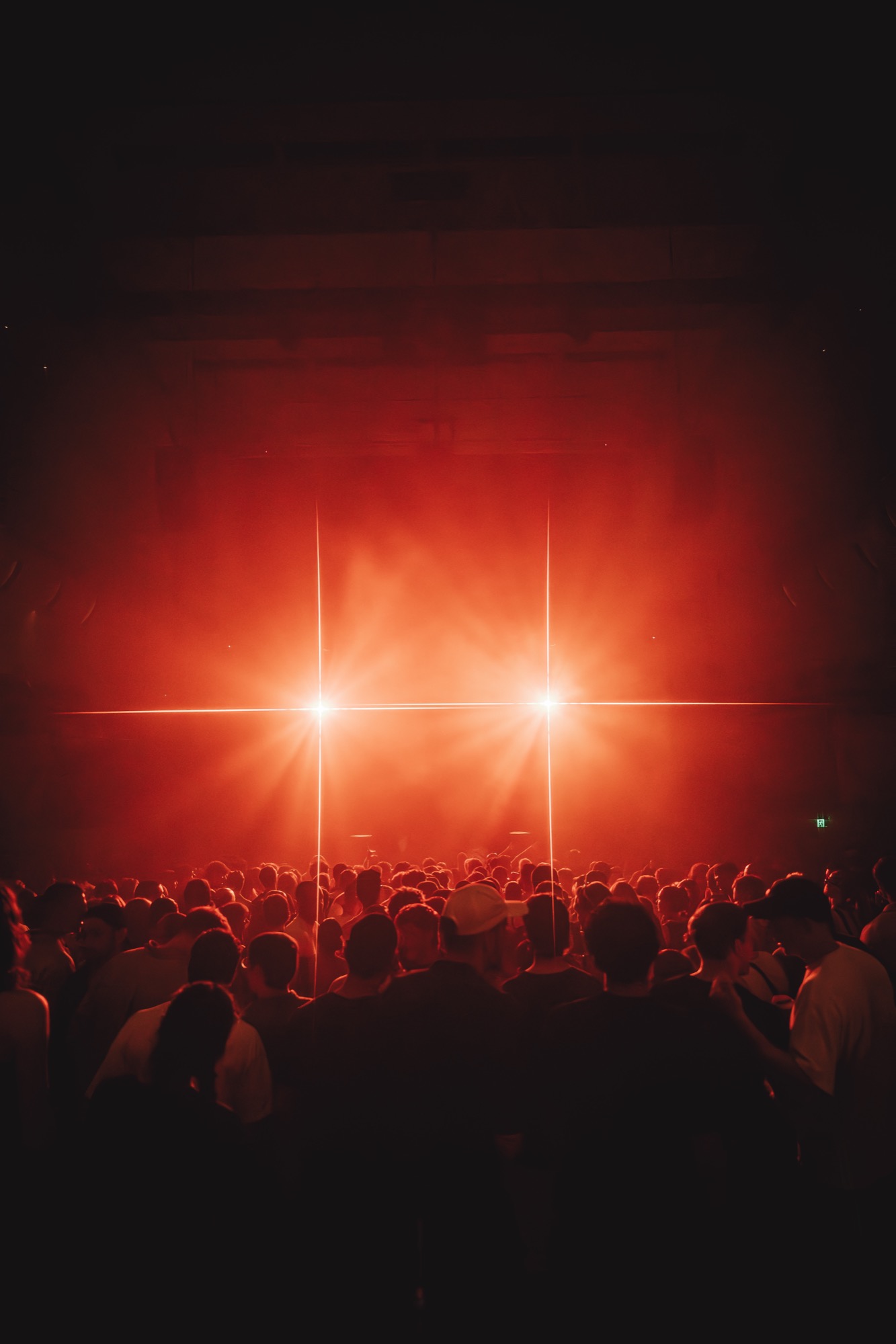 Red stage beams over a concert crowd
